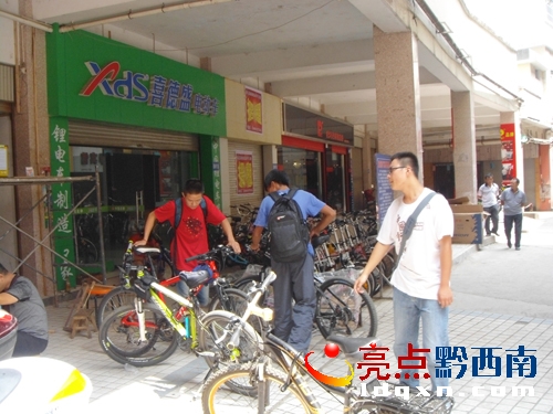 ★您好！敬請(qǐng)修改�。▓D2）騎行游，是健身低碳環(huán)保休假不錯(cuò)的選擇，圖為在興義市盤江路上檢修單車的“騎友”。（李勁松   攝